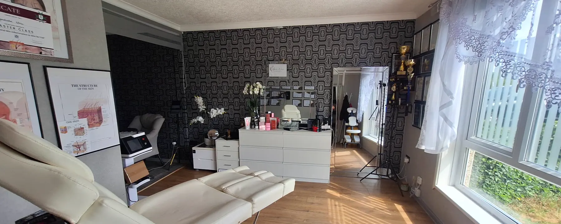 Jasny gabinet Agnes Beauty z fotelem zabiegowym, storczykami i słońcem wpadającym przez duże okno